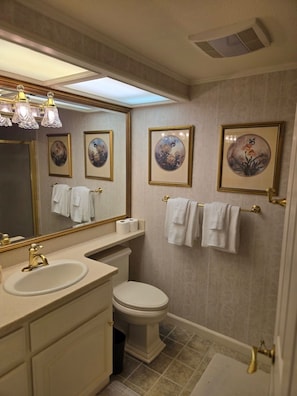 Une salle de bain avec un meuble-lavabo, des toilettes et une œuvre d’art florale encadrée au mur.