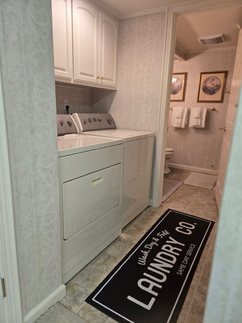 A laundry room with a washing machine, dryer, and a door mat with "Laundry Co." text.