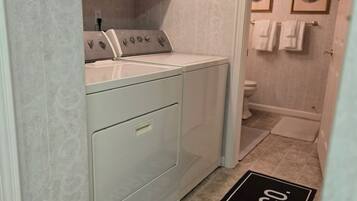 A laundry room with a washing machine, dryer, and a door mat with "Laundry Co." text.