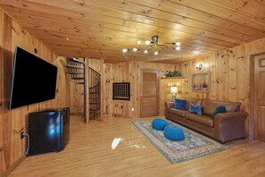 Un interior de madera con televisor, sofá y una escalera.