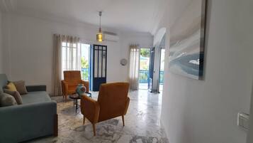 Una sala de estar con sofá, sillones, una mesa de centro y un cuadro en la pared.