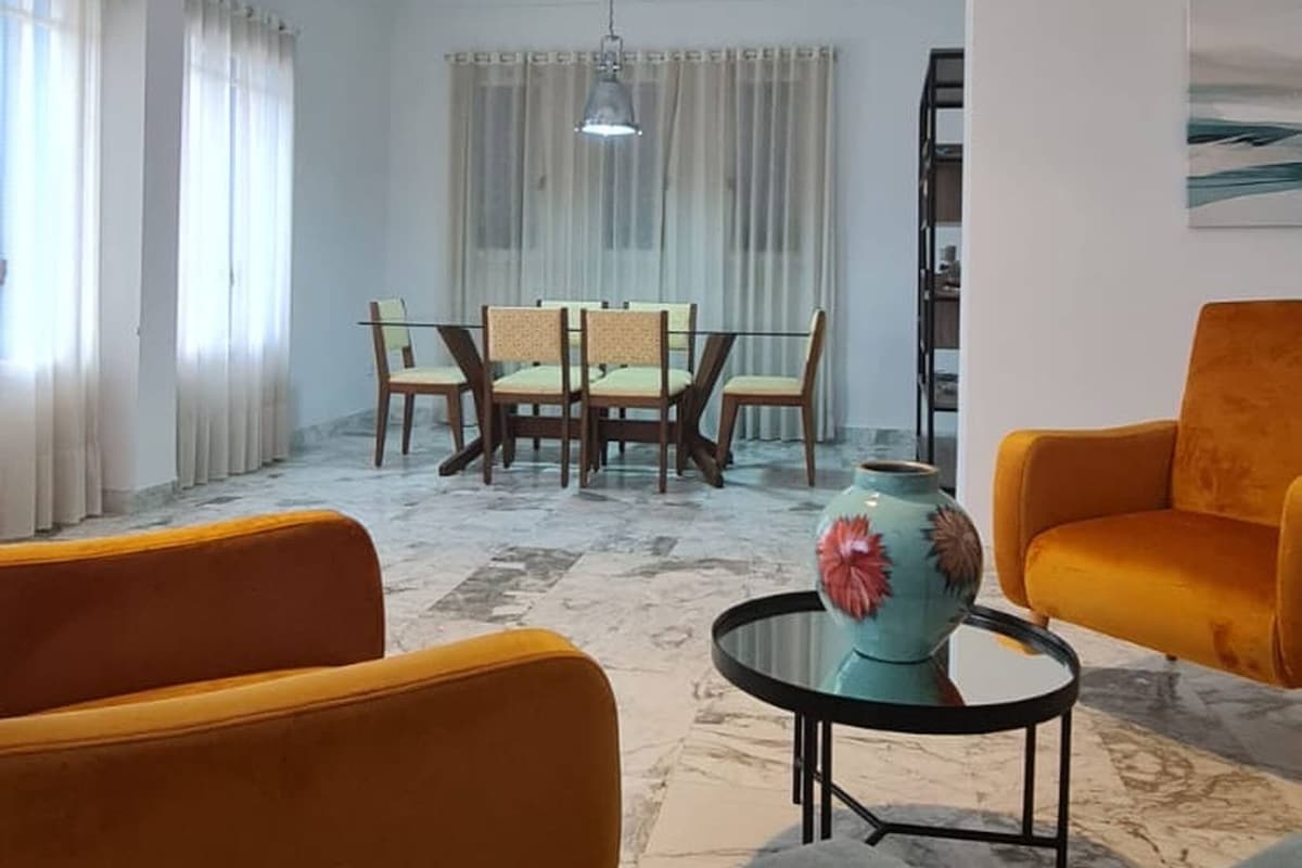 Una sala de estar con piso de mármol, dos sofás, una mesa de centro y un comedor con sillas y una mesa.