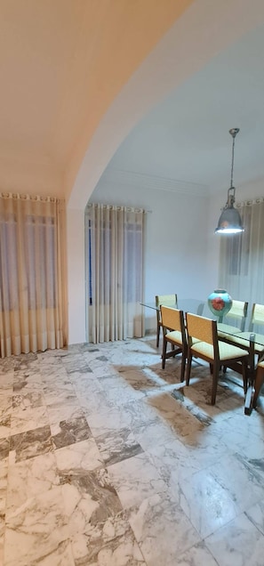Un comedor con una mesa de vidrio, sillas y una lámpara colgante.