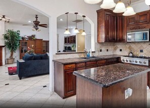 Una cocina con encimeras de granito, armarios de madera y estufa integrada.