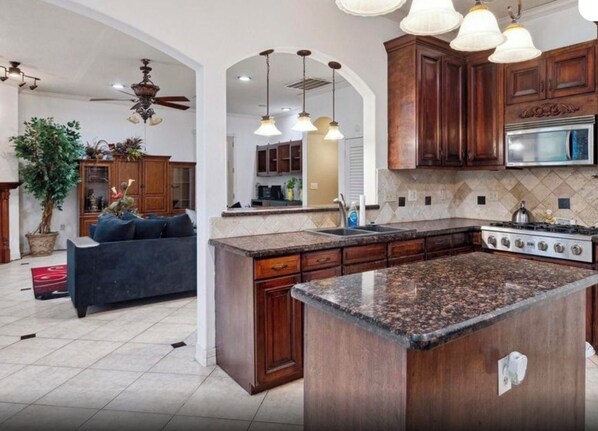 A kitchen with granite countertops, wooden cabinets, and a built-in stove.