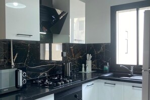 A modern kitchen with a gas stove, white cabinets, and a marble backsplash. - Modern & Comfortable 1-Bedroom Apartment With Private Parking & Prime Location (Tunis)