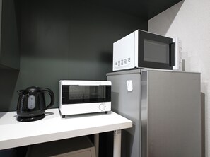A kitchen with a microwave, a kettle, and a refrigerator. - Common Table Okayama - 5 beds & 5 bikes (岡山市)
