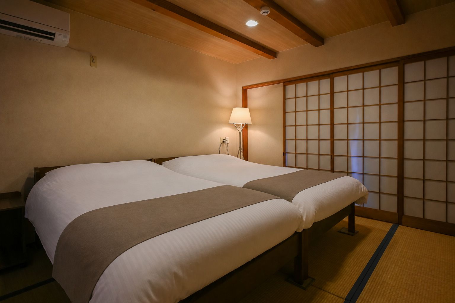 A hotel room with a traditional Japanese-style sliding door, a bed with a headboard, and a bedside lamp.