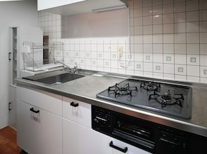 A kitchen with a stainless steel sink, a gas stove, and white cabinets. - Common Table Okayama - 5 beds & 5 bikes (岡山市)