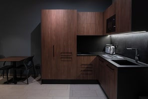 A modern kitchen with dark wood cabinets, a black countertop, and a built-in microwave. - Marea Grand Harbour  (Kalkara)