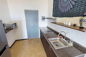 A compact kitchen with a microwave, a sink, and a door. - Cerritos Surf View (El Pescadero)