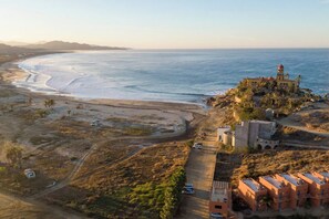 An aerial view of a coastal area with a beach, a tower, and buildings. - Cerritos Surf View (El Pescadero)