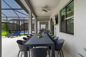 Ein moderner Innenraum mit einem langen Tisch, Stühlen, großen Fenstern und einem Deckenventilator.