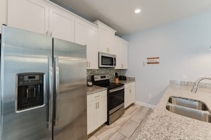 A kitchen with white cabinets, stainless steel appliances, a granite countertop, and a built-in microwave. - 5-bedroom House With Private Pool (Kissimmee)