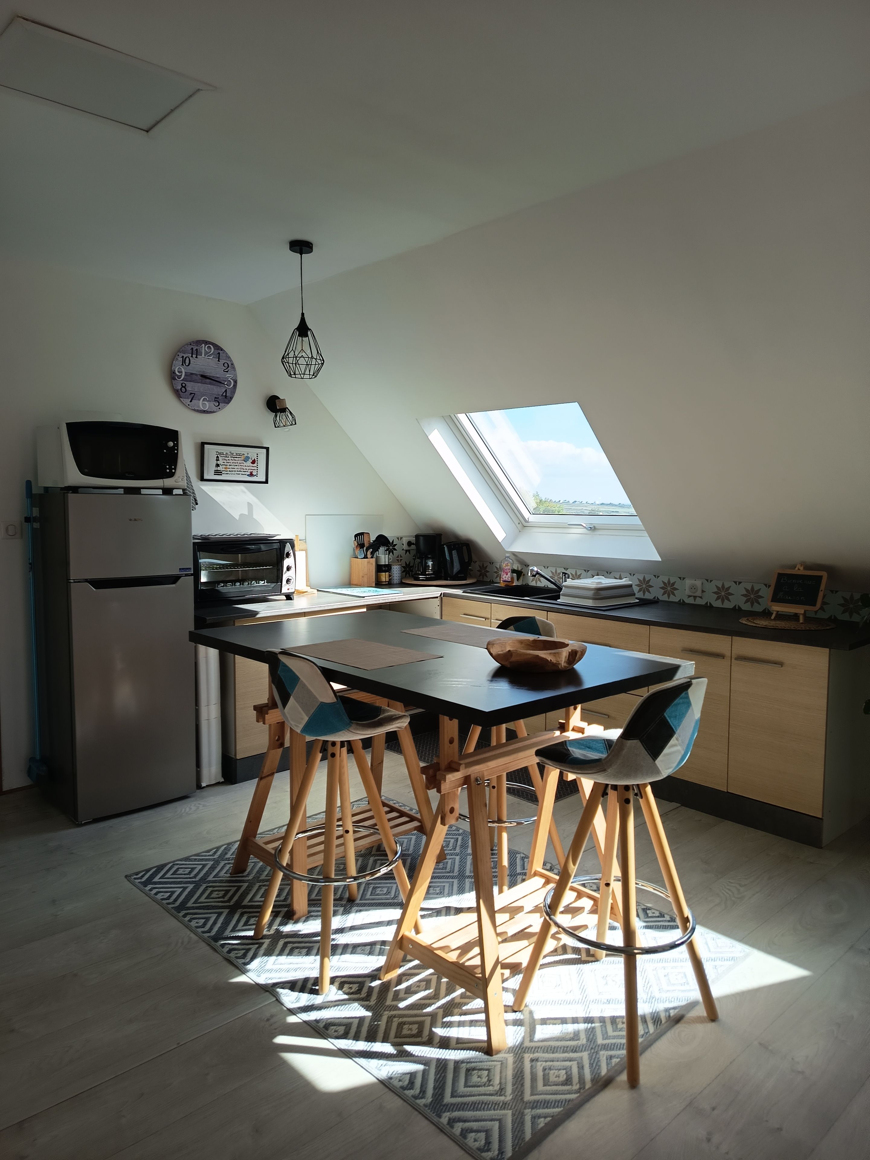 Una cocina moderna con tragaluz, un refrigerador, un microondas y un comedor con sillas y una mesa.