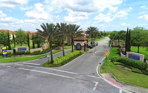 A road leading to a gated community with palm trees and a sign for 'Soterra'. - Luxury Home at Solterra Resort (Davenport)