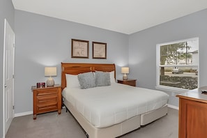 A bedroom with a bed, two bedside tables, a nightstand, a dresser, and a window with a view. - Stylish 4BR Townhome 10 Min to Disney (Kissimmee)