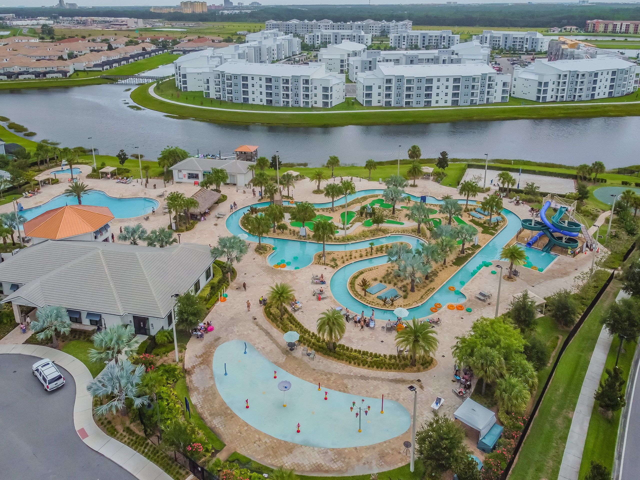 A resort with a large swimming pool, water slides, and a lake.