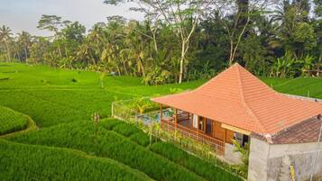 Uma casa com telhado cerâmico, rodeada por campos verdes e árvores.