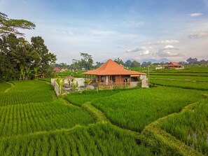 A house with a red roof surrounded by lush green rice paddies. - Villa Suda Ubud by Dhananjaya (Ubud)