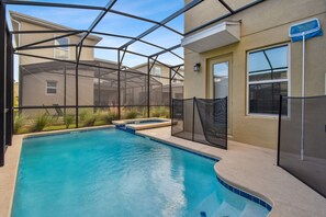 A swimming pool with a covered area, surrounded by a beige building with a window and a door. - 5BR Storey Lake Home, Pool & Game Room (Kissimmee)