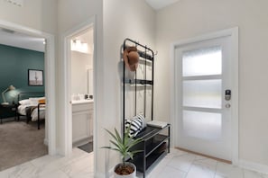 Un couloir avec un banc, un porte-manteau et une porte dont les panneaux sont en verre dépoli.