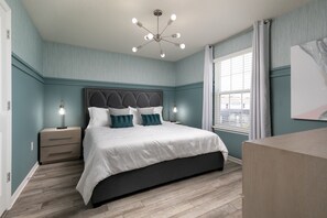 Ein Schlafzimmer mit einem großen Bett, einem Nachttisch, einer Kommode und einer Deckenleuchte.