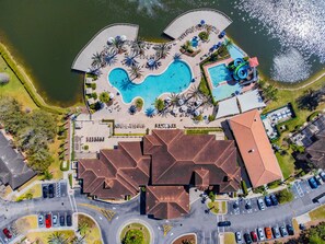 An aerial view of a resort with multiple swimming pools, a parking area, and a large building with a red roof. - 2BR Regal Oaks Townhome With Jacuzzi (Kissimmee)