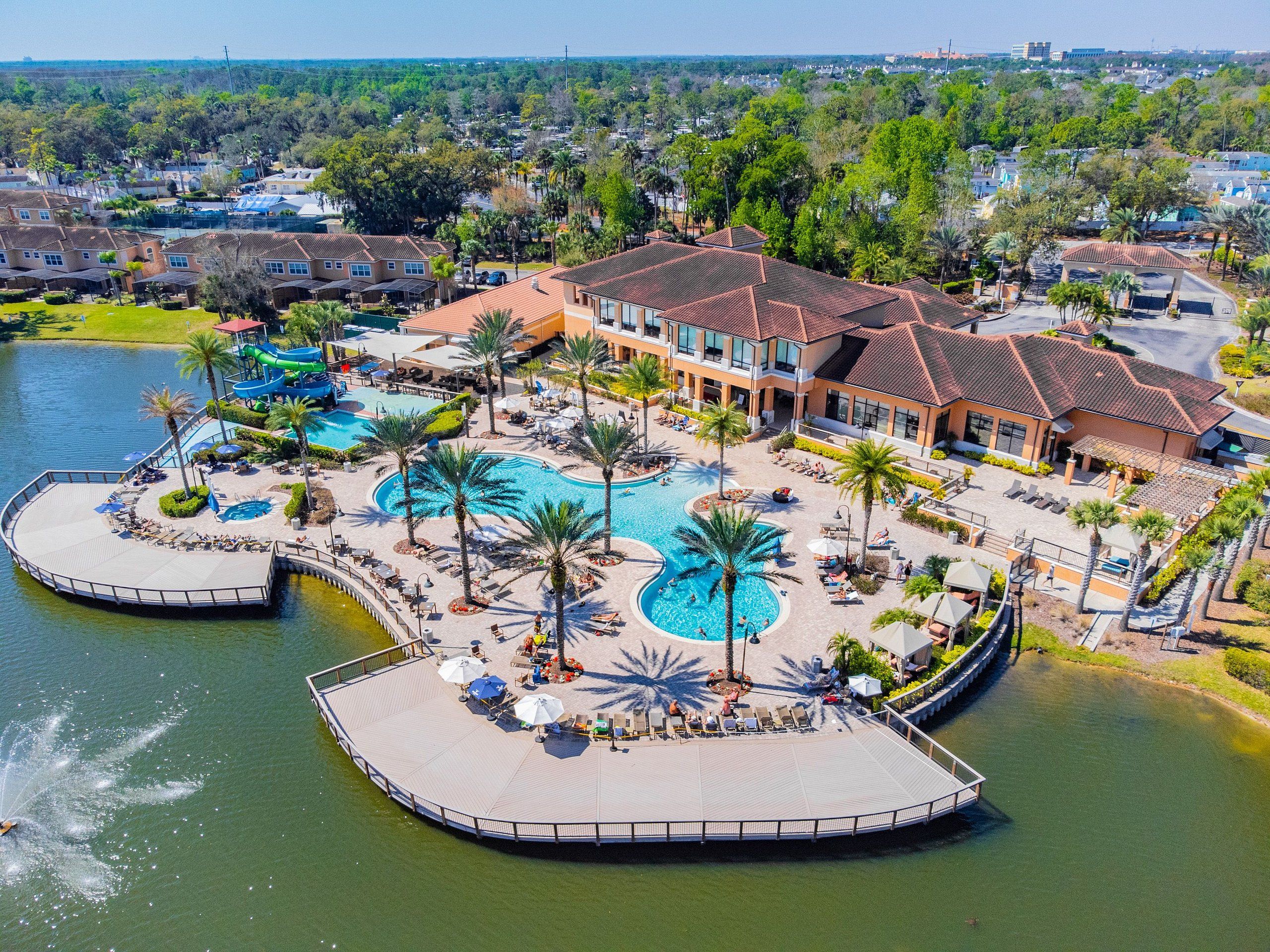 A resort with multiple swimming pools, palm trees, and a dock.