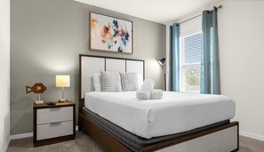 A neatly arranged bedroom with a bed, bedside table, lamp, and artwork on the wall. - 5BR Villa w/ Pool + Resort Access Solterra (Davenport)