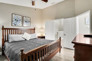 A bedroom with a wooden bed, a nightstand, a lamp, and a dresser. - Windsor Hills 3BR Home w/ Pool Near Disney (Kissimmee)