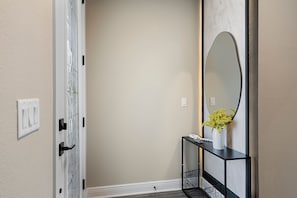 A hallway with a white door, a black console table with a potted plant, and a large mirror on the wall. - Reunion 4BR Luxury Villa PS5 + Game Room (Kissimmee)
