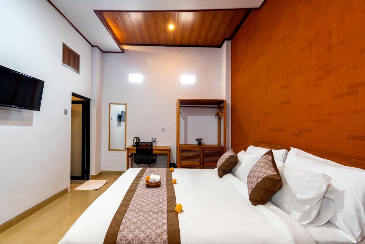 A hotel room with a bed, a desk, a chair, a television, and a mirror.
