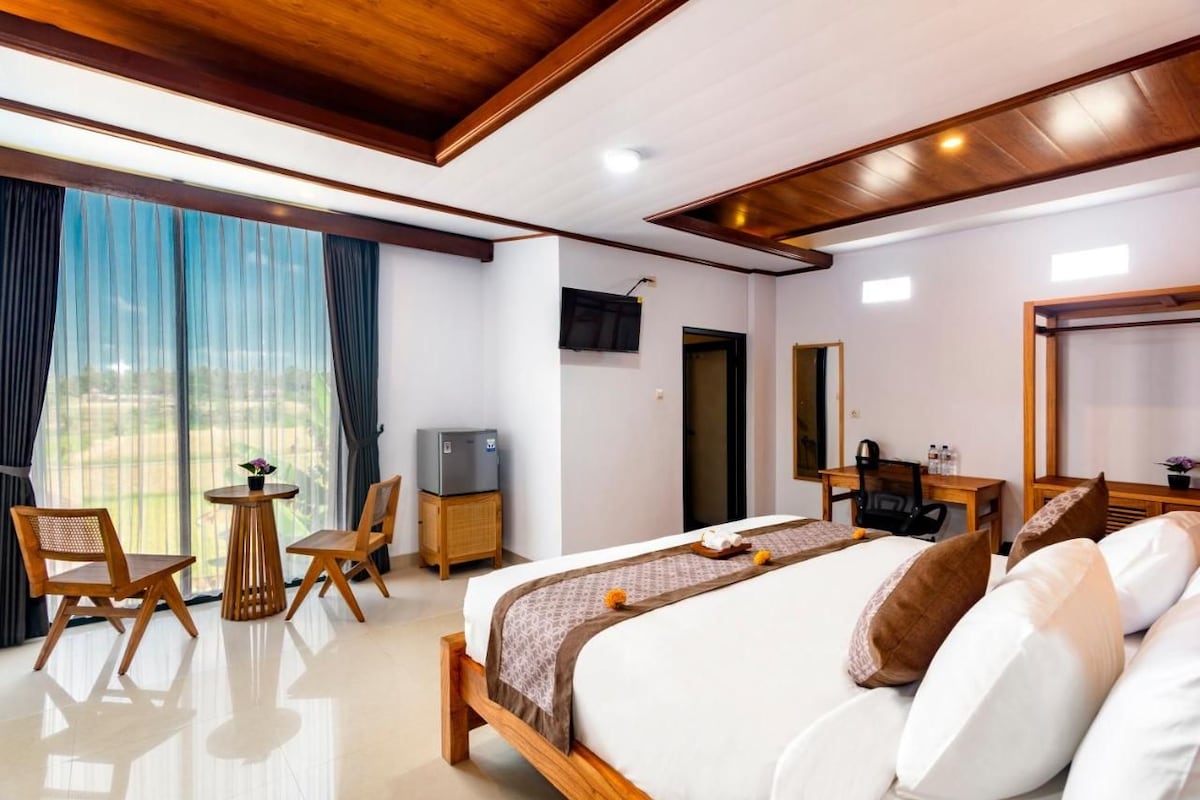 A hotel room with a bed, a desk, a chair, a television, and a window with curtains.