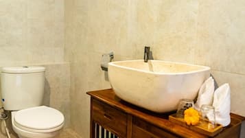 Ein Badezimmer mit Toilette, einem großzügigen Waschtisch und einer Holz-Kommode mit Handtuch und Blume.