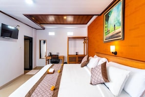A hotel room with a bed, a desk, a chair, a television, and a painting on the wall. - Manikawana House by Dhananjaya (Ubud)
