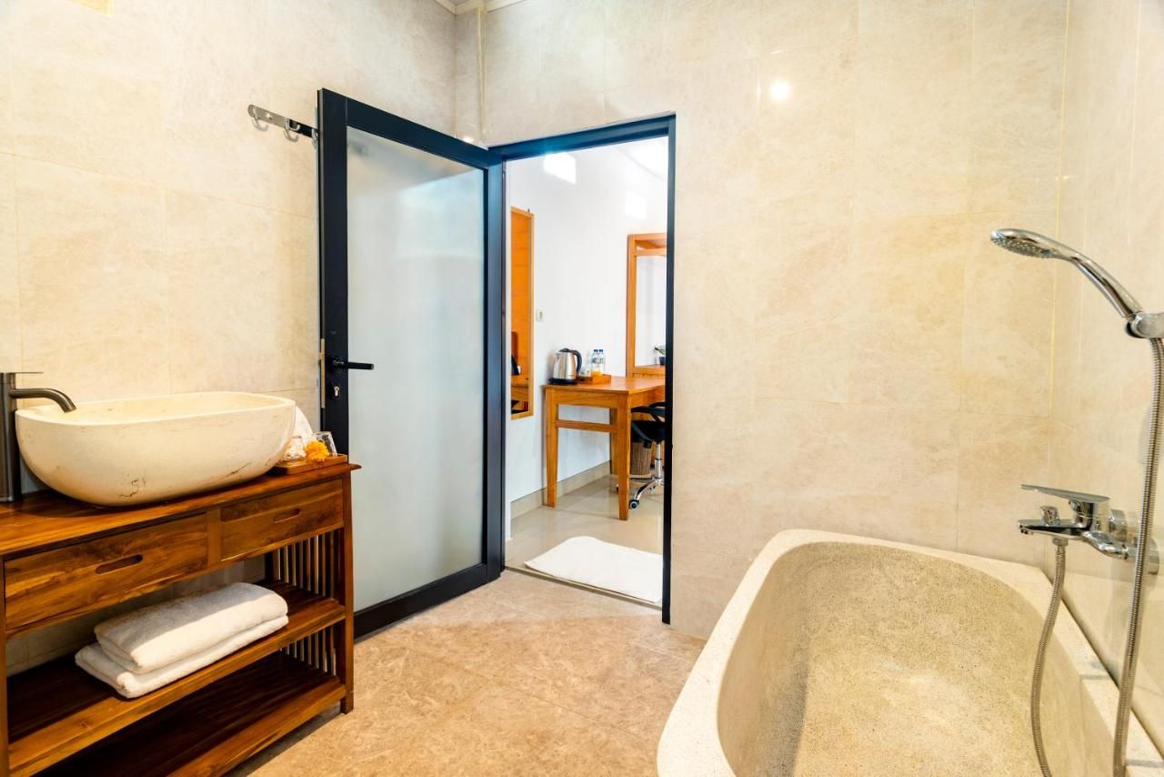 Un baño con una bañera independiente, un tocador de madera con un lavabo de diseño y una puerta que da a otra habitación.