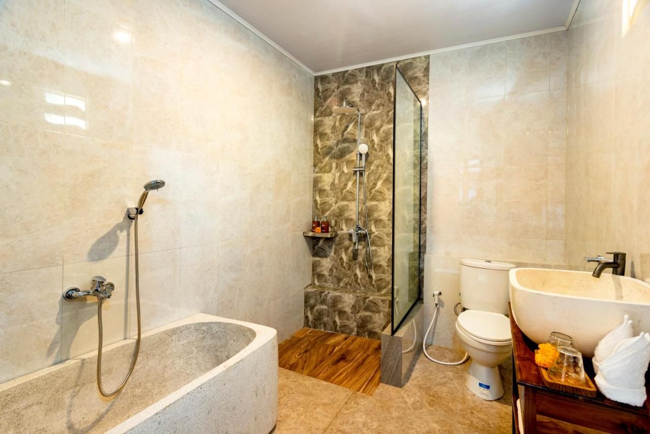 A modern bathroom with a freestanding bathtub, a glass-enclosed shower, a toilet, and a sink with a large basin.