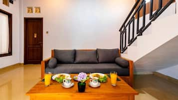 Ein Zimmer mit einem Holztisch, der für das Frühstück gedeckt ist, einem grauen Sofa und einer Treppe.
