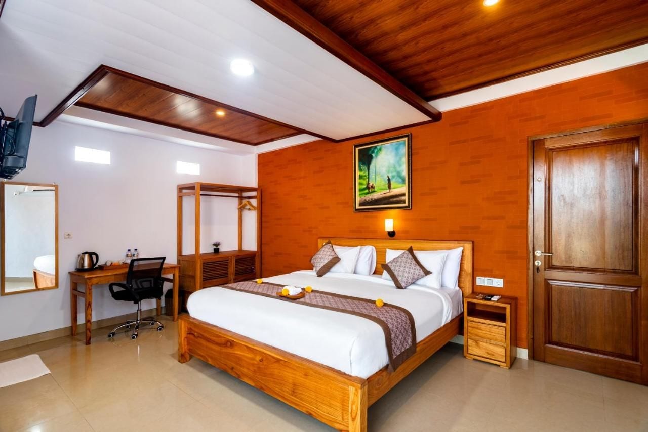 Una habitación de hotel con una cama de madera, un escritorio, una silla, una mesita de noche y una puerta.