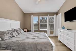 A bedroom with a bed, a dresser, a television, and a window with curtains. - Windsor Hills 3BR Pool,8min to Disney & Water Park (Kissimmee)