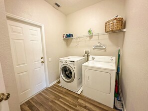 A laundry room with two washing machines, a shelf with laundry supplies, and a mop leaning against the wall. - Windsor Hills 6BR Villa w/ Pool & Game Room (Kissimmee)
