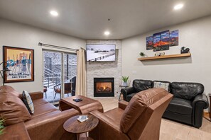 A modern living room with leather sofas, a fireplace, and a ski-themed artwork. - Steps to Hot Tub, King Suite, Free Shuttle, Gas Fireplace | Moose Mgmt 4206 (Park City)
