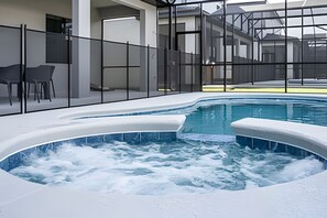 Ein Whirlpool mit angrenzendem Poolbereich, umgeben von einer Glasumrandung.