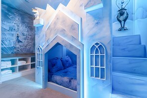 Ein Kinderzimmer mit einem Bett, Einbauschränken und einer Wandmalerei einer verschneiten Landschaft.