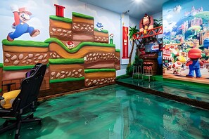A room with a Mario-themed mural, a small pool, and a seating area. - Luxury 6BR Villa Prime Location, Pool & Cinema (Orlando)