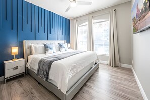 A modern bedroom with a bed, nightstand, and a ceiling fan. - Windsor Hills 4BR Pool Home + Mario Game Room (Kissimmee)