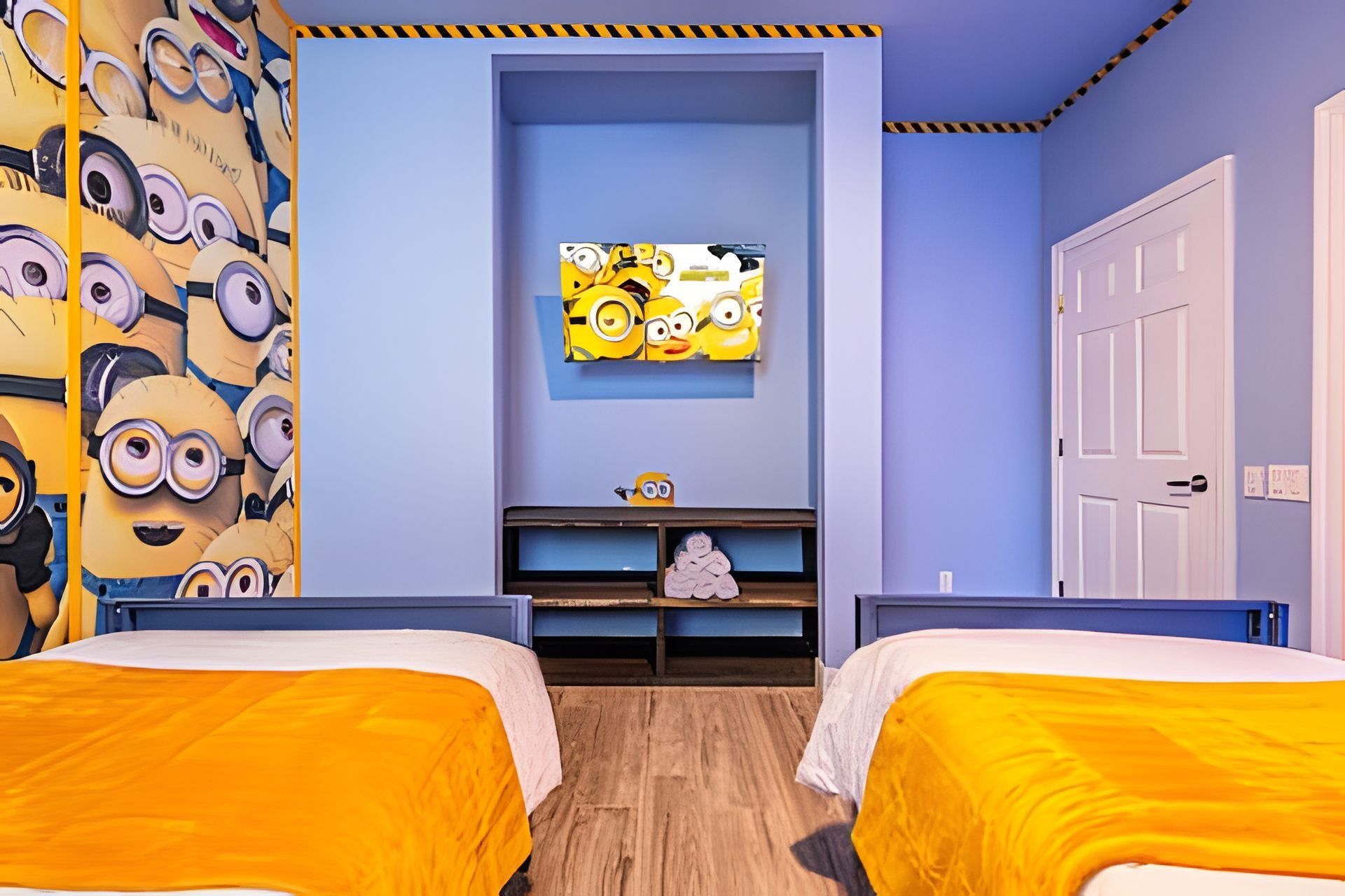 A bedroom with two beds, a wall-mounted TV, a door, and a shelf with a figurine.
