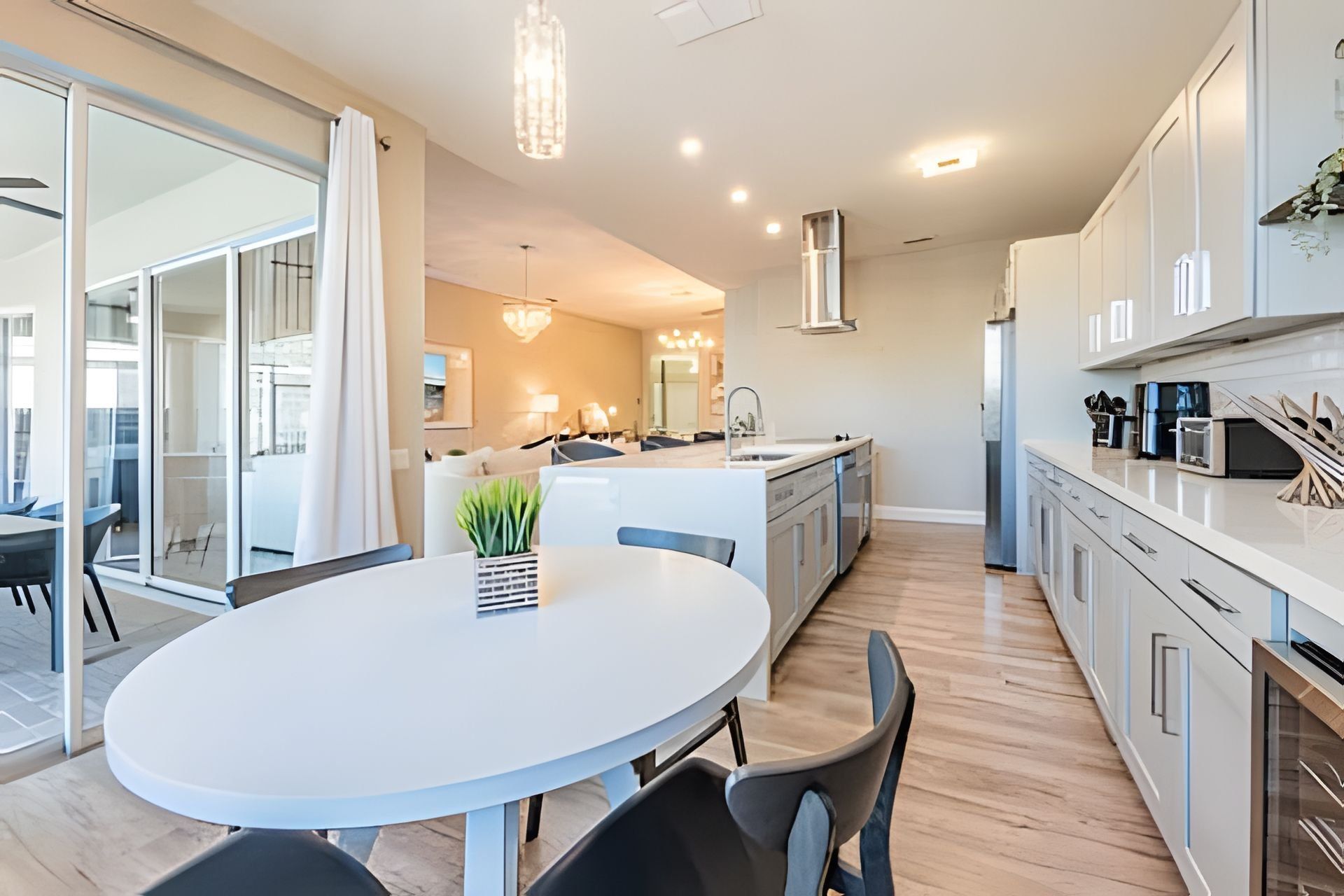 Una cocina moderna con armarios blancos, una isla central y un comedor con una mesa redonda y sillas.