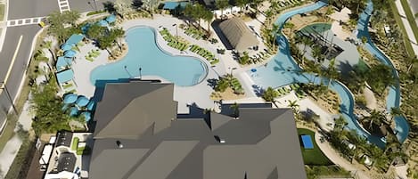 An aerial view of a resort with a large swimming pool, landscaped areas, and a parking lot.